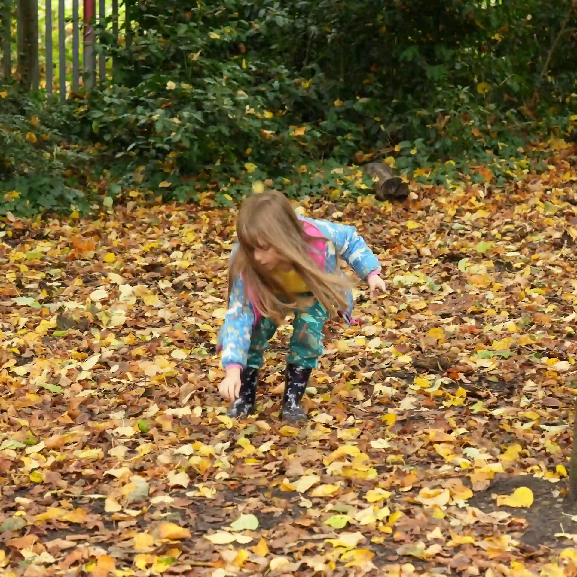 A girl stood outside searching through the leaves.