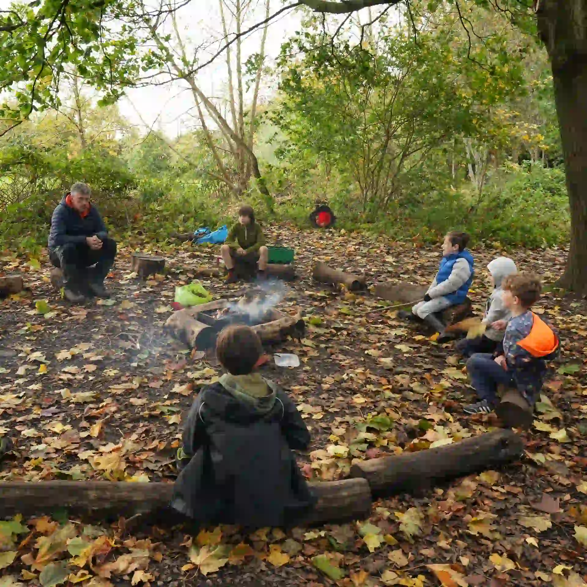 Children and worker sat in a circle around the campfire.