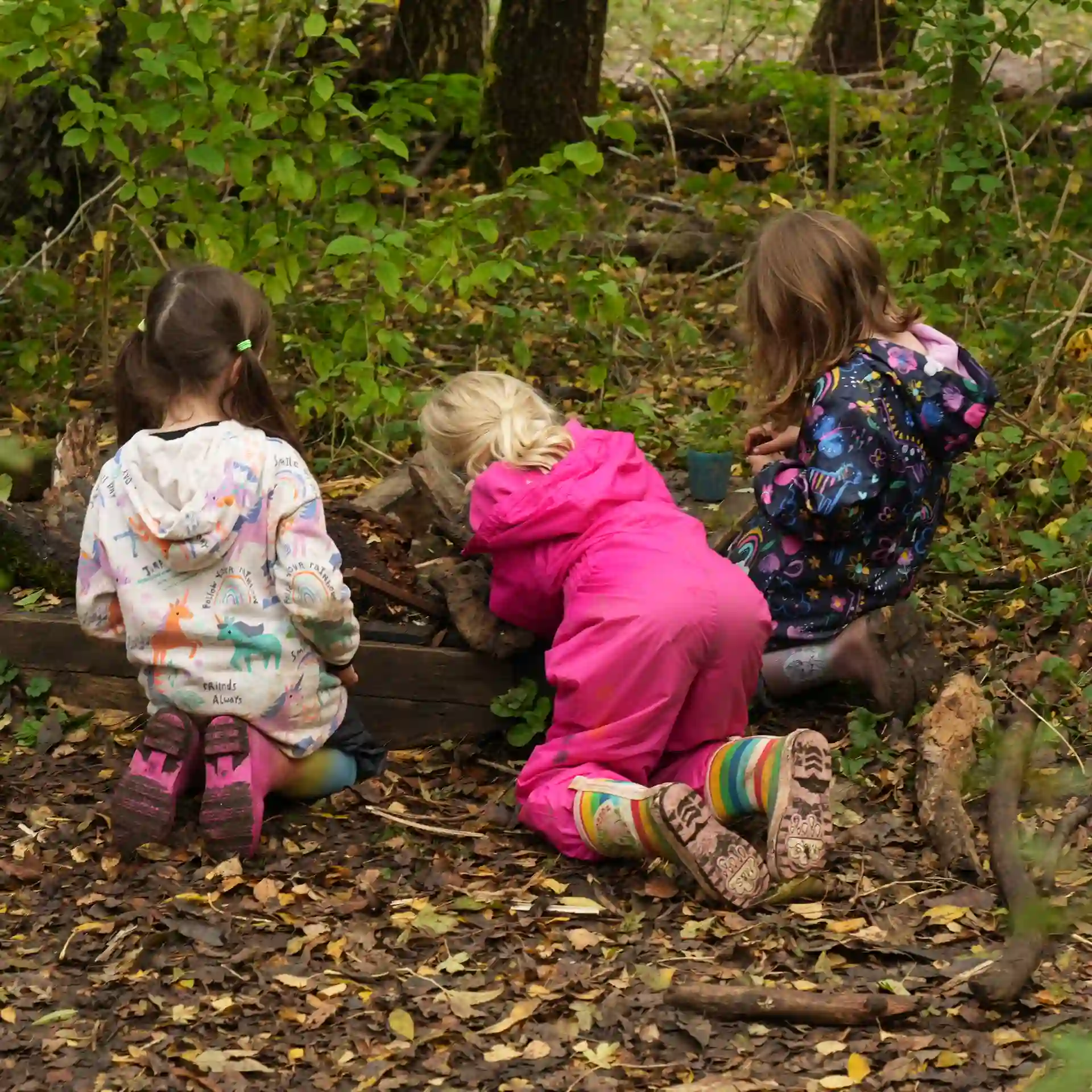 Three girls crouched together searching for wildlife.