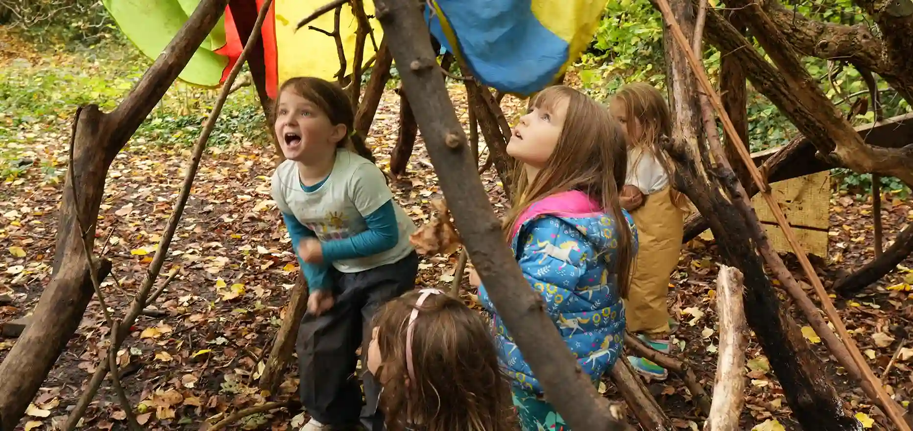 A group of children playing in a den in the forest.