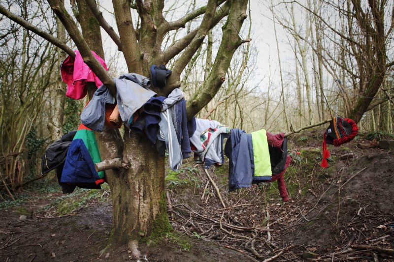 A range of different children's coats hanging up on a tree.