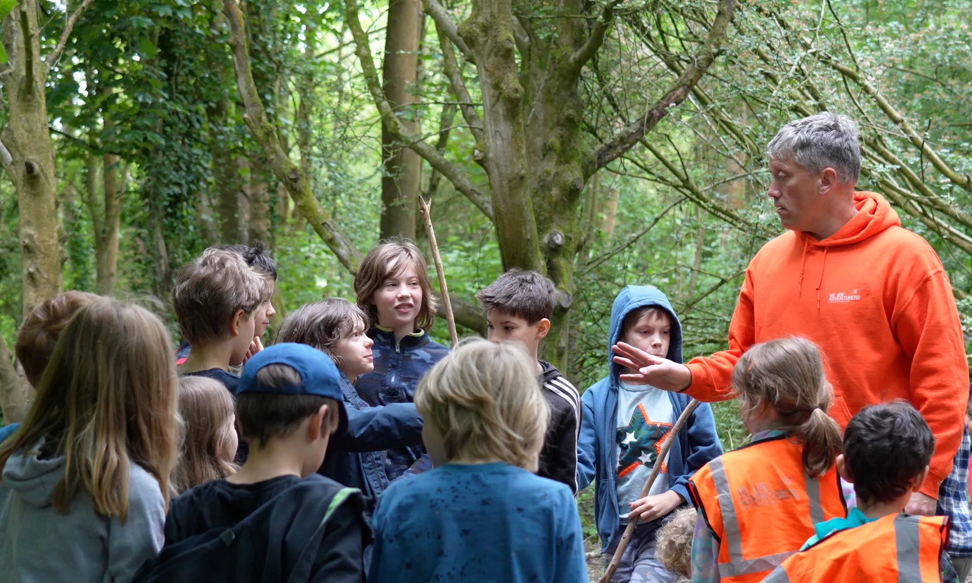 A class of children stood listening to the forest school teacher.