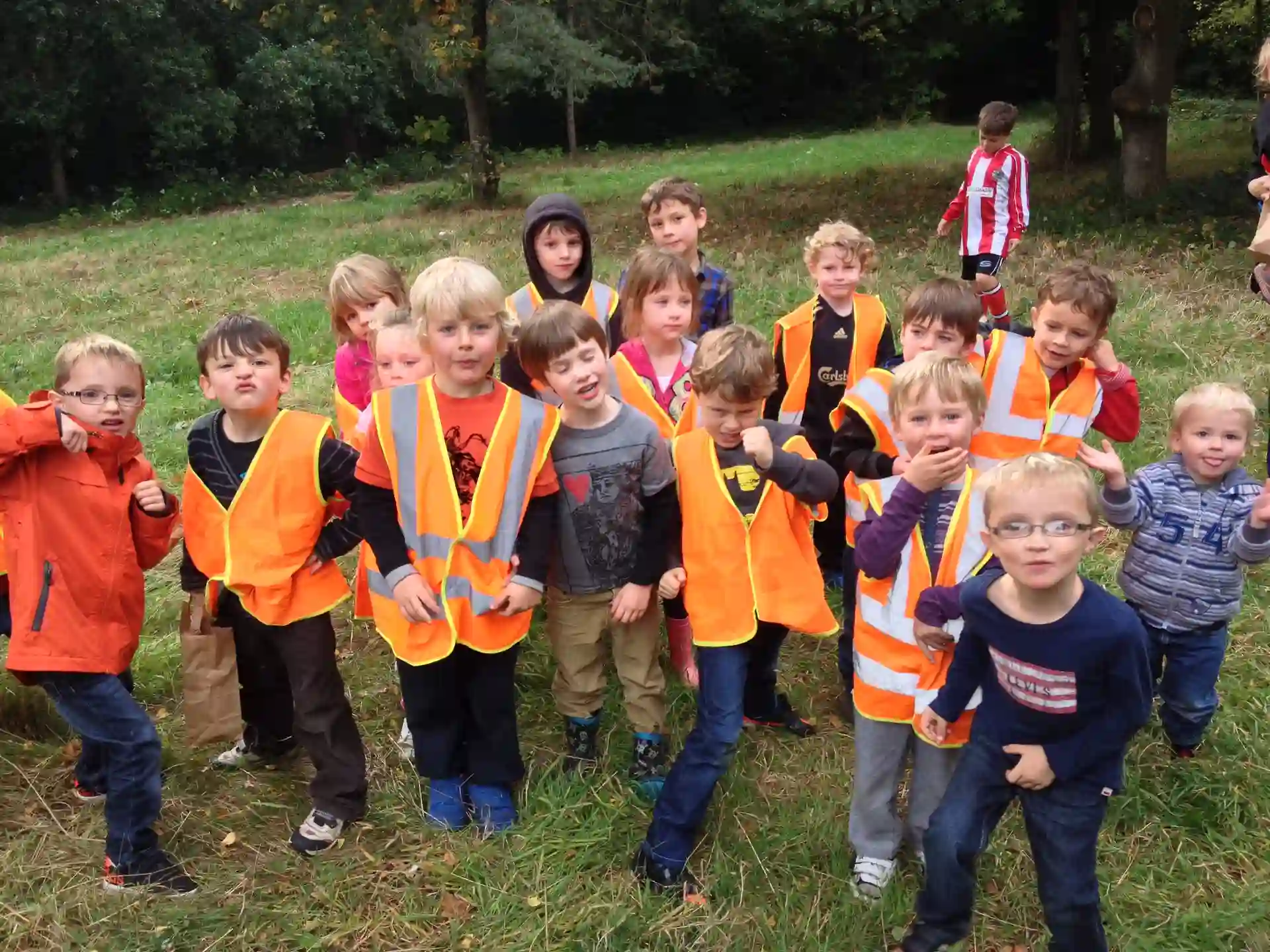A group of children in orange hi-vis posing for a photo.